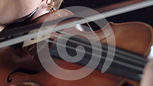 Girls in play the violins in a composition in a room. Black background. Close up