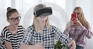 Girls playing game with virtual reality goggles and smartphone at home