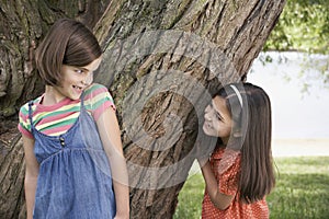 Girls Playing Hide And Seek By Tree photo