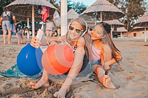 Girls playing with mobile phones on sandy beach