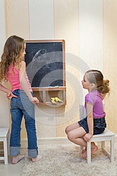 Girls in the playroom paint on the blackboard