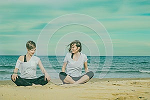 Girls practicing yoga on the beach