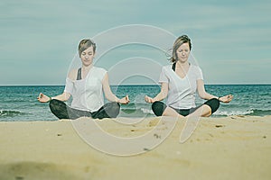 Girls practicing yoga on the beach