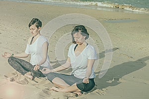 Girls practicing yoga on the beach