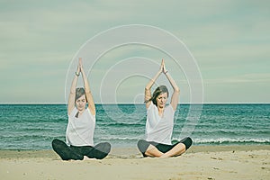 Girls practicing yoga on the beach