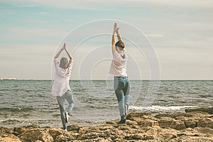 Girls practicing yoga poses on the beach. Healthy Lifestyle