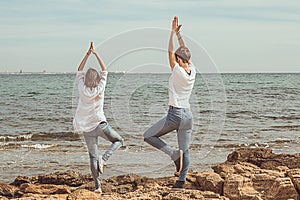 Girls practicing yoga poses on the beach. Healthy Lifestyle