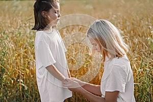 Girls praying and holding hands in a wheat field. Pray for God each other support together