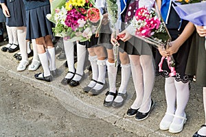 Girls primary school with bouquets of flowers in his hands. Shoes on her feet and white pantyhose, socks and stockings