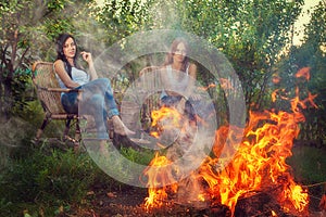 Girls with red wine glasses near bonfire