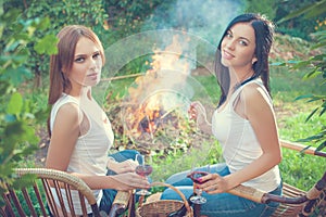 Girls with red wine glasses near bonfire