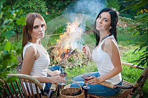 Girls with red wine glasses near bonfire