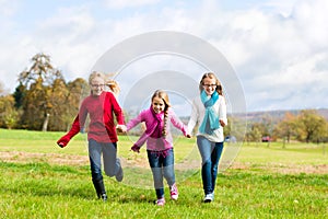Girls running through fall or autumn park