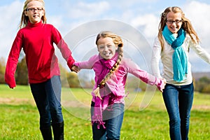 Girls running through fall or autumn park