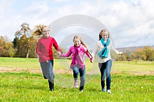 Girls running through fall or autumn park