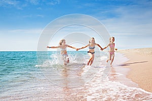 Girls running in sand and waves of sunny beach