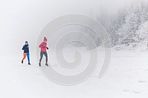 Girls running together on snow in winter mountains. Sport, fitness inspiration and motivation. Two women partners trail running in