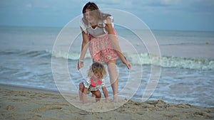 Girls runs to mother on beach. Happy family daughter and mom on sandy seashore. Beautiful sunrise and sunset