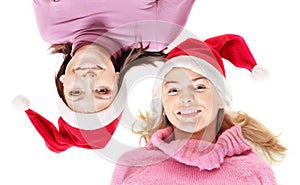 Girls in santa hat lying head next to head.