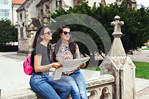 Girls searching for places on their map outdoors. Best girl friends traveling together in europe. Europe vacation, old city
