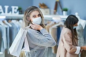 Girls on shopping in store with clothes wearing masks