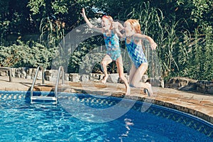 Girls sisters diving in water on home backyard pool. Children siblings friends enjoying and having fun in swimming pool together.