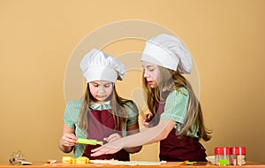 Girls sisters having fun ginger dough. Kids baking cookies together. Kids aprons and chef hats cooking. Homemade cookies