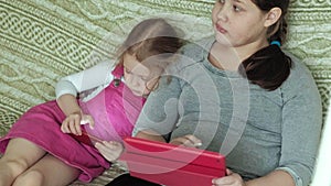 Girls sisters playing on the tablet in the room, web surfing, rest