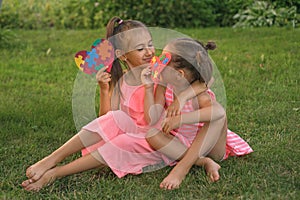 Girls sit on grass in park with postcards made in support of autistic people