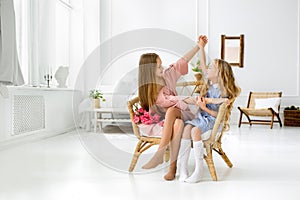 The girls sit together on a chair in the room with a bouquet of tulips. The friendship of two children.