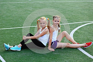 Girls sit on a twine on a sports field.