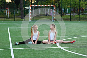 Girls sit on a twine on a sports field.