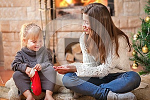 Girls sitting fireside opening Christmas presents photo