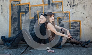 Girls sitting in front of graffiti wall