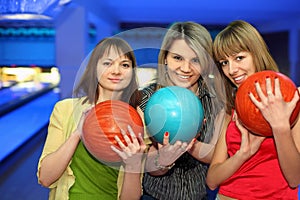 Girls stand alongside, hold balls for bowling photo