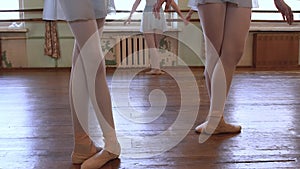 Girls stand in third position and begin to dance in ballet classroom.
