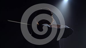 Girls standing back and playing the violins in a dark room. Black smoke background