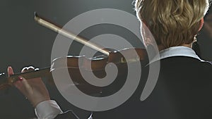 Girls standing back and playing the violins in a dark room. Black smoke background. Close up