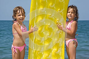 Girls standing on beach with inflatable mattress