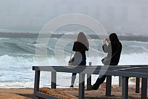 Girls taking photos of a sea storm