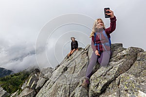 Girls taking selfies on top of a Rocky Mountain