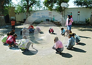 Girls with teacher playing a game at playground at school