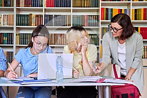 Girls teenage students studying in library with teacher mentor