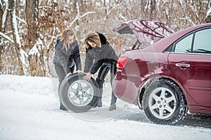 Girls trying to repair the car, engine repair, tire change. Female using changing wheel. Womans changing the punctured