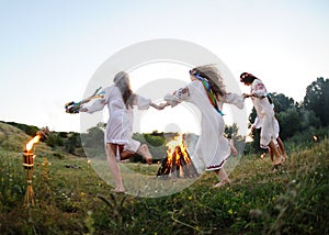 Girls in Ukrainian national shirts dancing around a campfire. Midsumer