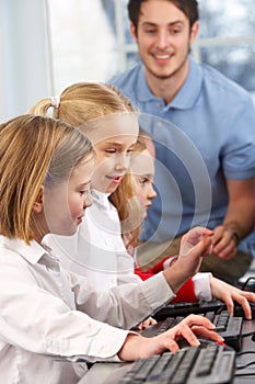 Girls using computers in class with teacher