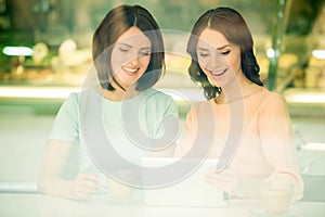 Girls using tablet in cafe