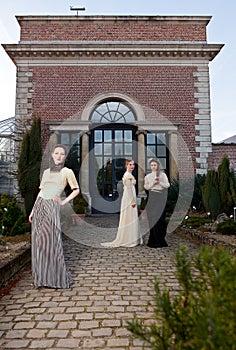 Girls in Victorian outfits in front of old house