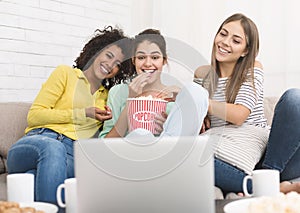 Girls watching comedy movie and eating popcorn at home