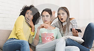 Girls watching horror movie on tv at home